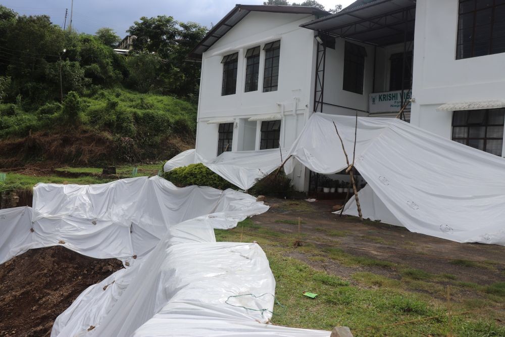 A protective tarpaulin is seen covering the landslide-affected area at the KVK Zunheboto facility at Nagaland University’s Lumami Campus on August 11. The facility remains threatened by a landslide following the collapse of its retaining wall and farm road on July 31. (Morung Photo)
